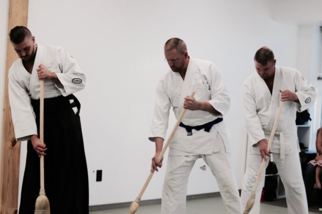 Aikido students using brooms in class